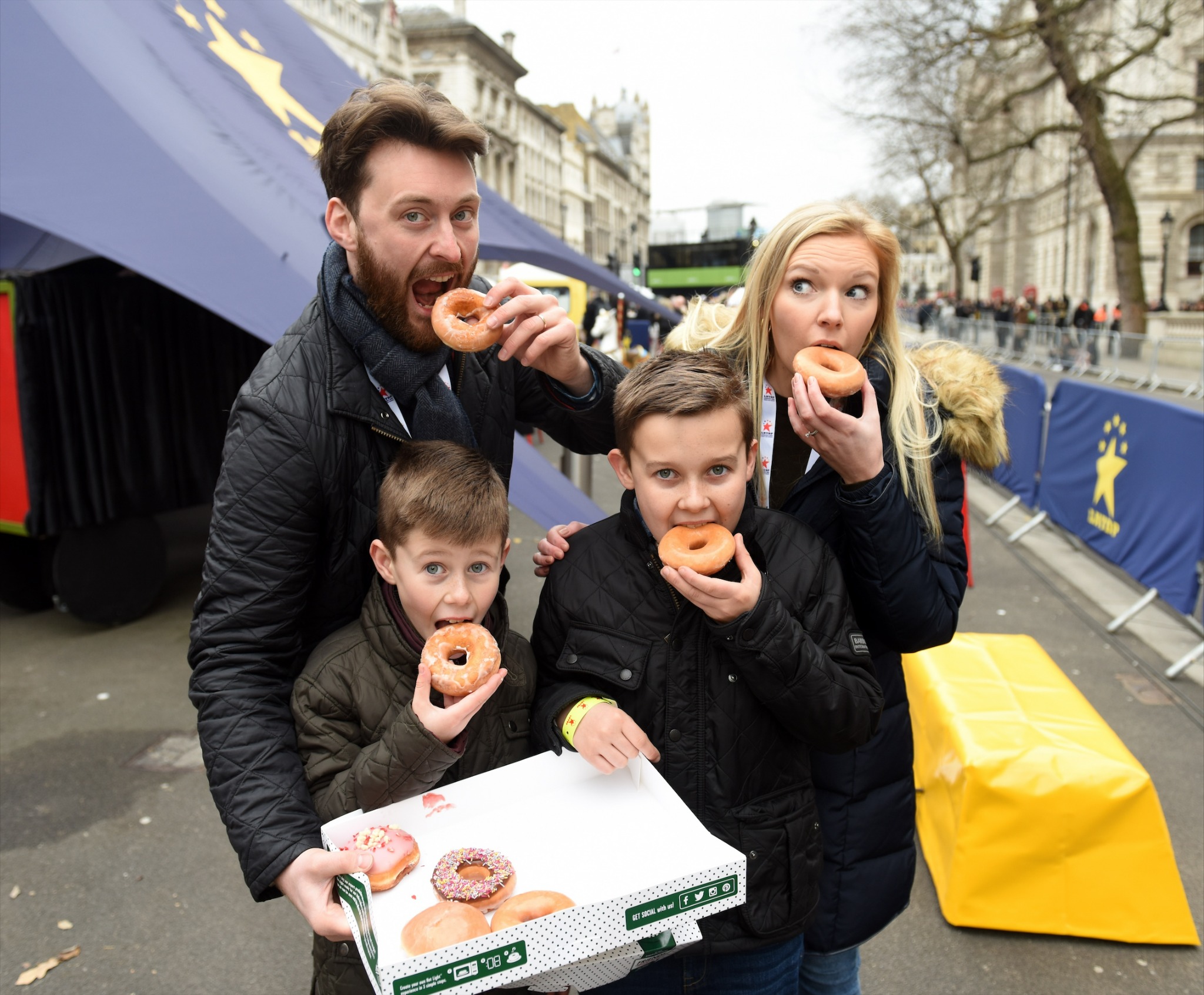 Family enjoying doughnuts at a London street event.
